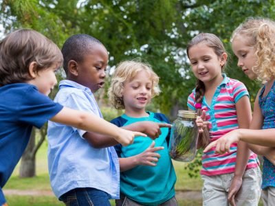 Happy siblings looking at a jar on a sunny day